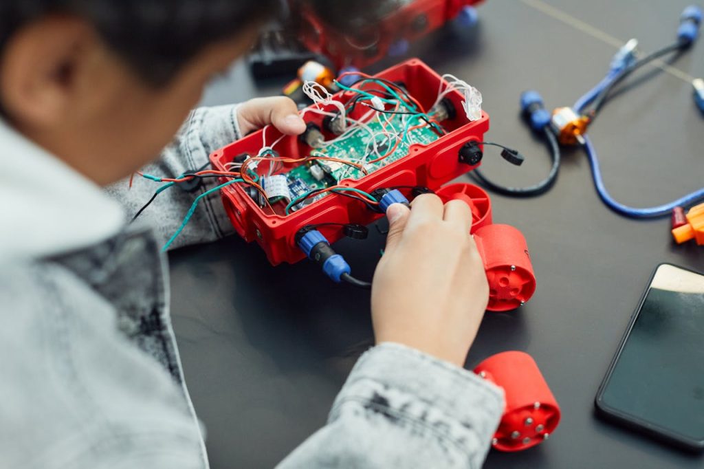 a-person-doing-his-project-7869034 A child actively assembling a robotics project with electronic components, showcasing technology education.